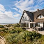 Ferienhaus mit Reetdach in Dünenlage am Meer – Symbolbild für den Verkauf einer Ferienimmobilie. | Immobilienverkauf